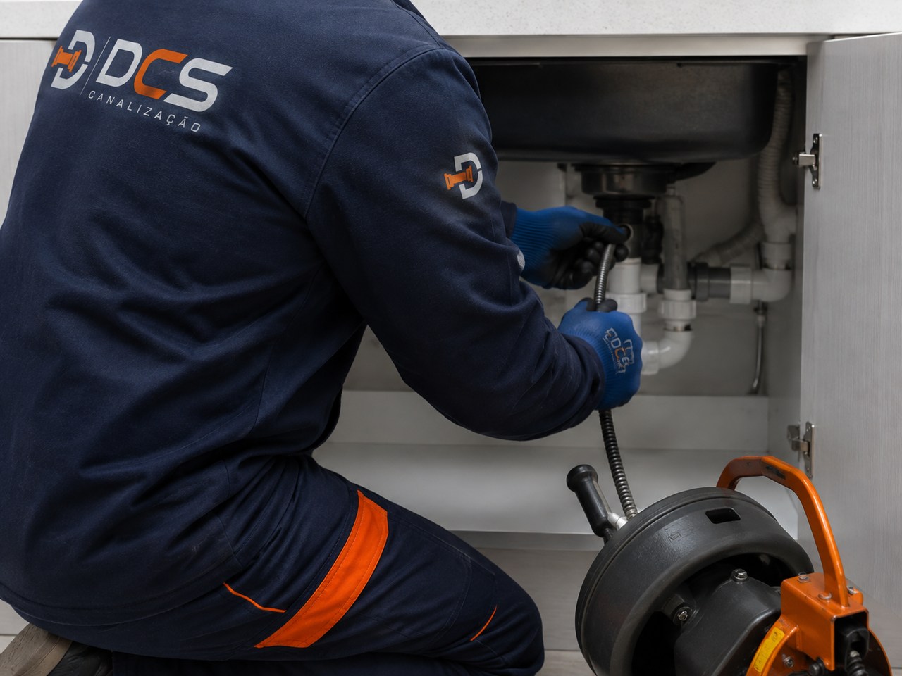 Técnico DCS realizando desentupimento sob a pia